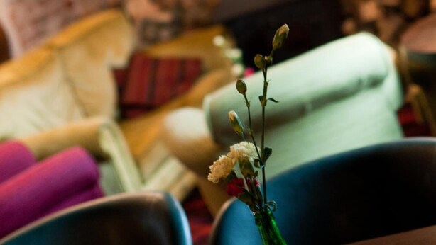 Un salon chaleureux avec une cheminée, un canapé vert et un vase rempli de fleurs posé sur une table.