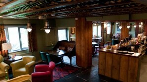 Un espace bar avec des meubles en bois, un comptoir où sont exposées des bouteilles, et un coin salon avec des chaises et un canapé.