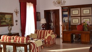 Una habitación tradicional con un conjunto de sofás, un escritorio de madera y una araña.