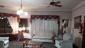 Un salon comprenant un canapé, deux fauteuils, une table basse, un ventilateur de plafond et une lampe.
