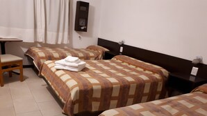 Une chambre d’hôtel avec trois lits, un bureau et une chaise.