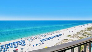 A beach with rows of blue umbrellas and sun loungers, a clear blue sky, and the ocean. - The Oasis 1209 | Spacious! Lazy River, Pool Slide, Poolside Grill! (Orange Beach)