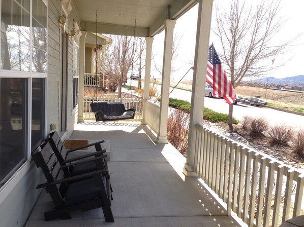 A porch with a swing, a bench, and an American flag.