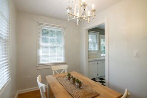 A dining area with a wooden table, white chairs, and a chandelier. - Windsor Bungalow Retreat- come for work and relaxation (Sarasota)