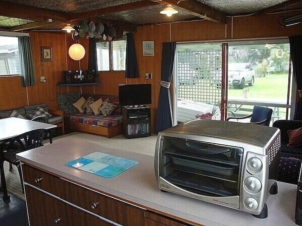A compact kitchen with a built-in toaster oven, wooden cabinets, a dining table, and a sofa.