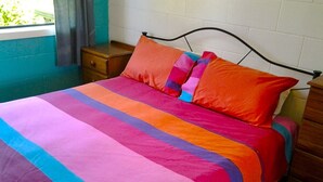 Ein Bett mit einer farbenfrohen, gestreiften Tagesdecke und zwei Kissen.