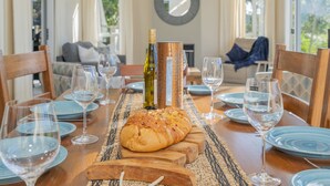 Une table à manger dressée avec des assiettes, des verres et une miche de pain.