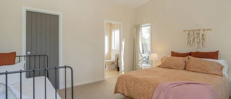 Ein Schlafzimmer mit Bett, Nachttisch, Lampe und Fenster.