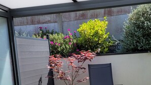 Un patio al aire libre con césped artificial verde, muebles de mimbre y plantas en macetas.