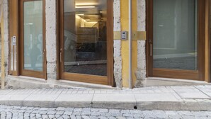 A building facade with two wooden doors, a glass window, and a plaque on the wall. - Go2oporto A-Portoments (Porto)