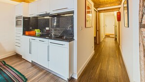 A modern kitchen with white cabinets, a stainless steel refrigerator, and a black countertop. - Go2oporto A-Portoments (Porto)