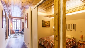 A hallway leading to a bedroom with a bed, a door, and a wall with a barcode. - Go2oporto A-Portoments (Porto)