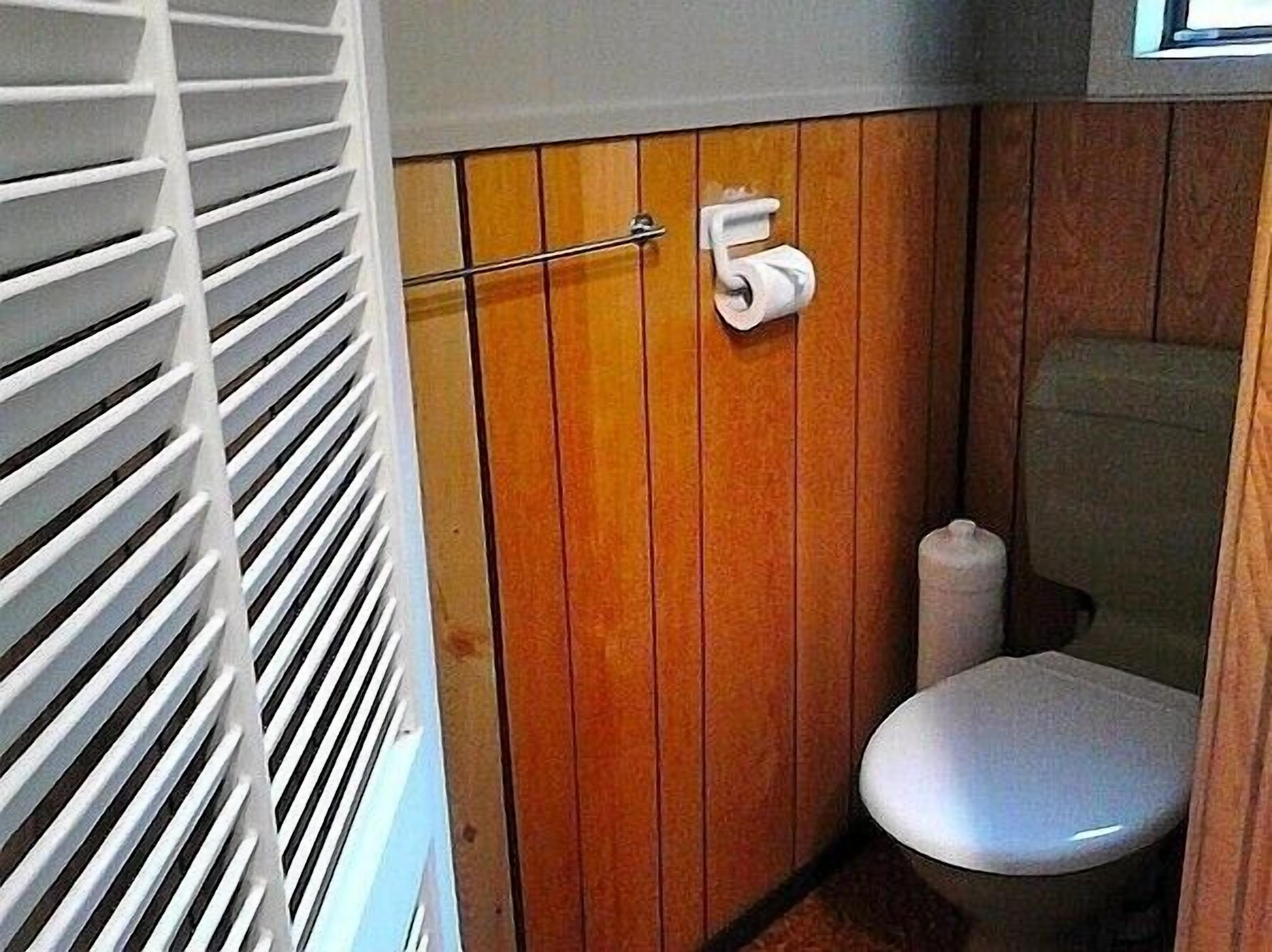 Une petite salle de bain avec un meuble-lavabo en bois, des toilettes et un porte-rouleau de papier toilette.