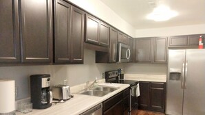 A modern kitchen with dark cabinets, stainless steel appliances, and a marble countertop. - Inviting Condo in Central Raleigh (Raleigh)