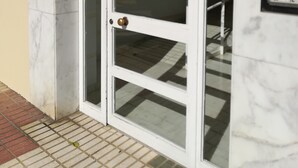 A white glass door with a brass handle, a mailbox on the wall, and a security keypad on the right. - Apartment on the beach in Rincón de la Victoria. (Rincón de la Victoria)