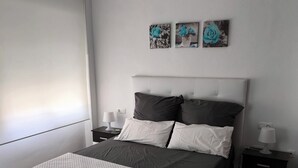 A modern bedroom with a large bed, two bedside tables, and a window with blinds. - Apartment on the beach in Rincón de la Victoria. (Rincón de la Victoria)