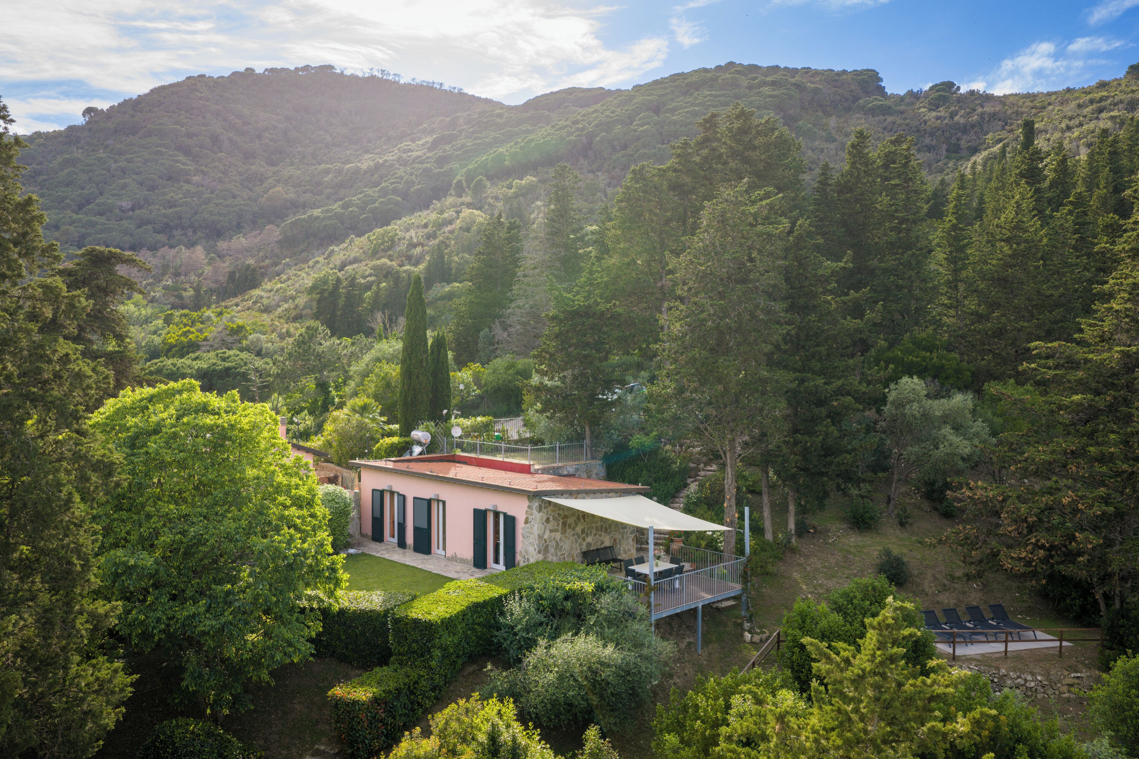 Una casa con facciata in pietra, un balcone e vista su una valle rigogliosa.