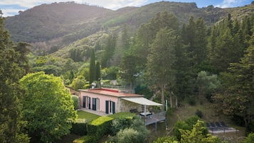 Una casa con facciata in pietra, un balcone e vista su una valle rigogliosa.