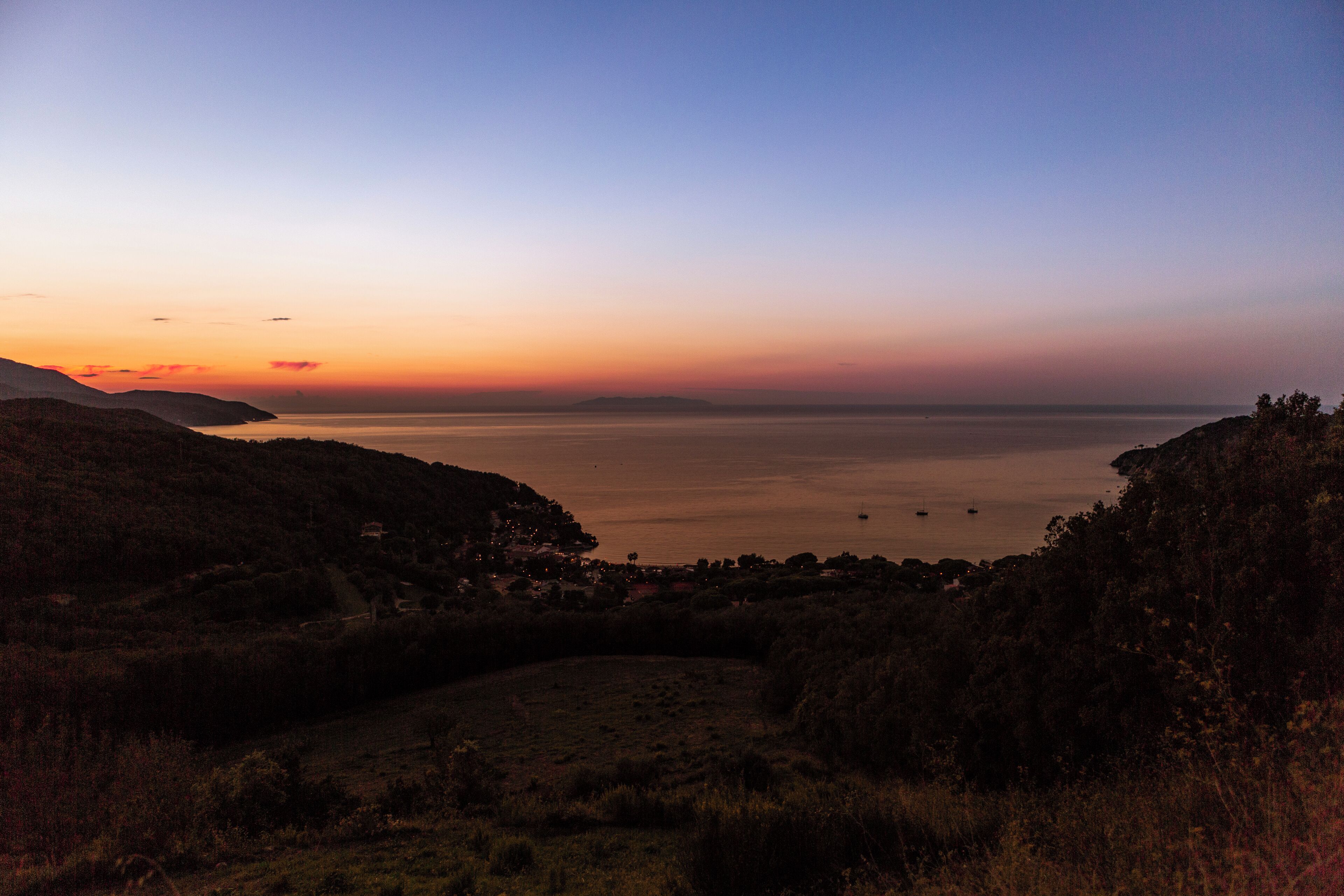 A coastal landscape with a view of the sea and distant hills.