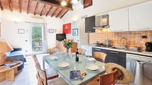 A modern kitchen with a dining area, featuring a large table set for four, a coffee machine, and a dishwasher. - Villette San Martino (Portoferraio)