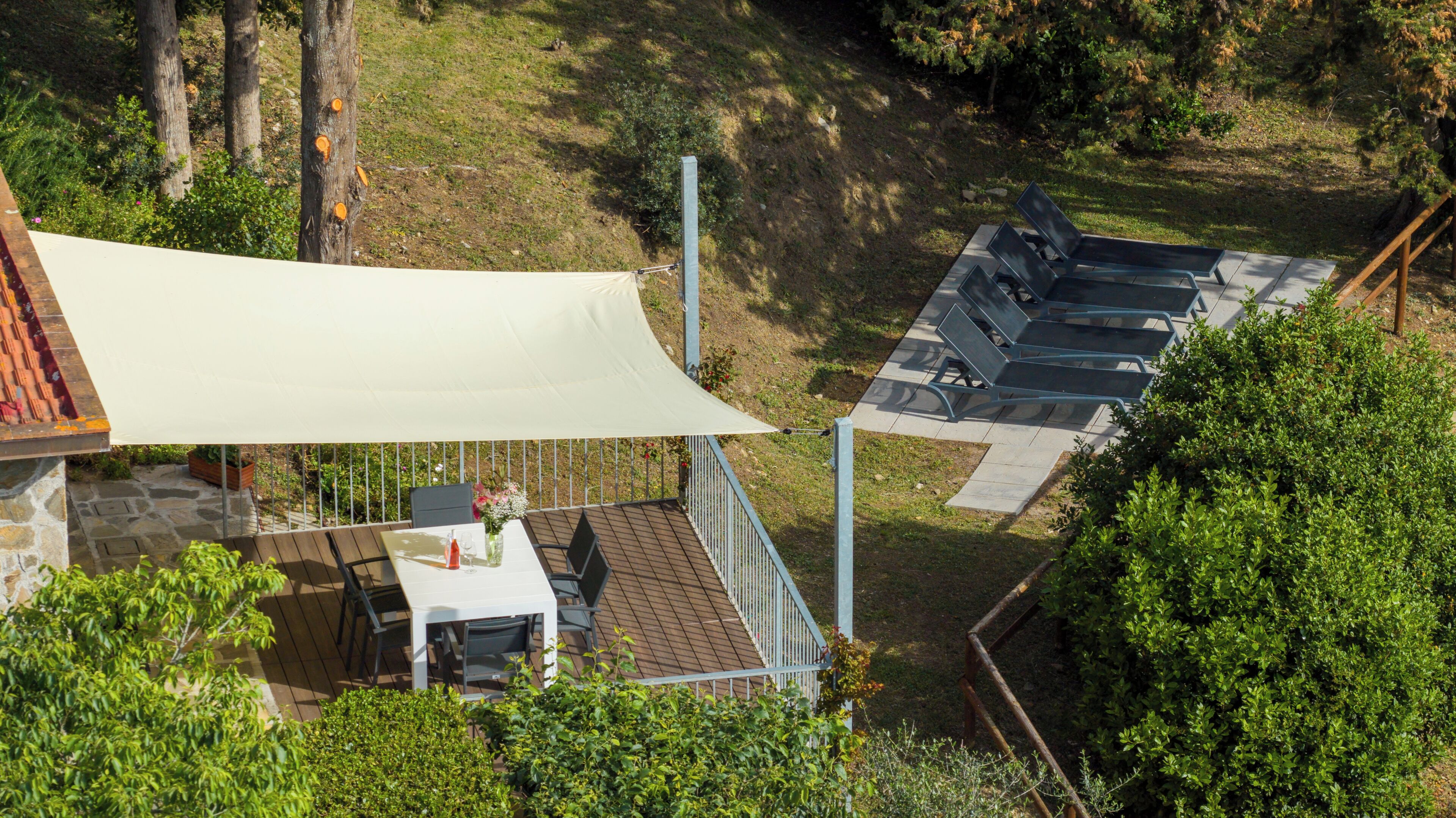 A rooftop terrace with a table and chairs, a canopy, and a seating area with metal chairs.