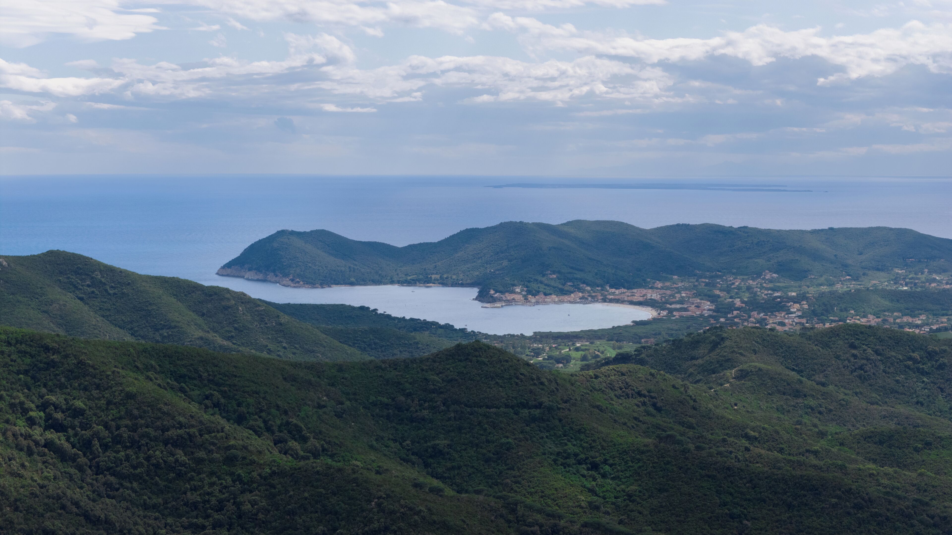 Un paysage côtier avec des collines, une baie et une petite ville.