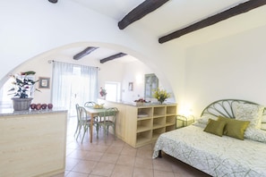 A cozy room with a bed, a wooden desk, and a dining area.