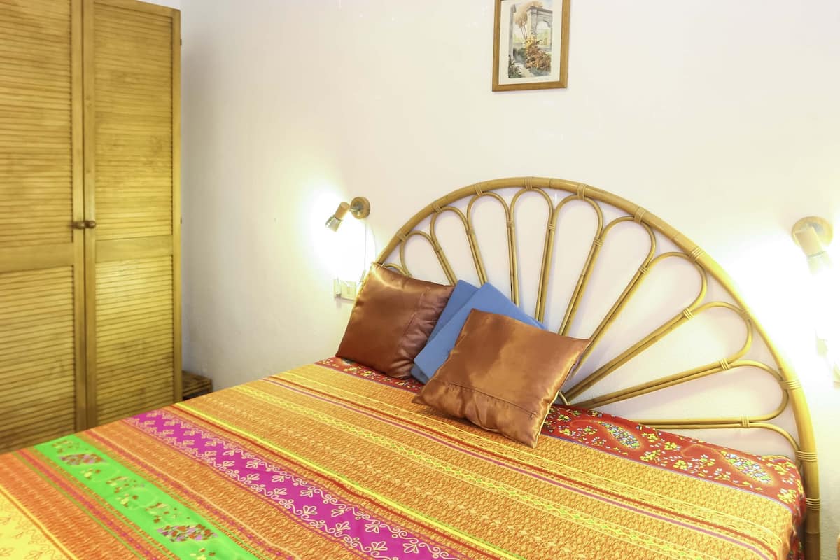 Un lit avec une couvre-lit à motifs, une tête de lit et deux oreillers.