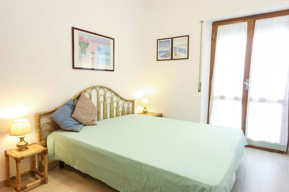 Une chambre à coucher avec un lit, deux lampes de chevet et deux tableaux encadrés accrochés au mur.