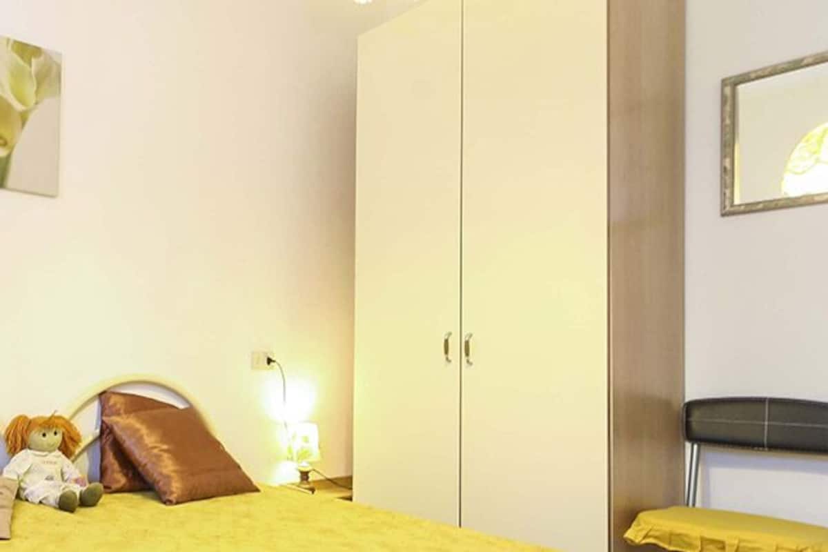 Une chambre à coucher avec un lit, une chaise, une armoire et une lampe.