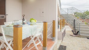 Un coin repas avec une table dressée pour deux personnes, des chaises et une vue sur l’extérieur.