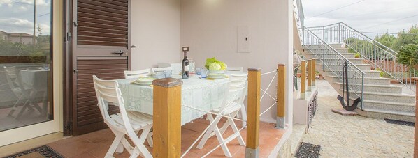 A dining area with a table set for two, chairs, and a view of the outside.