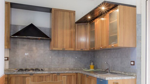 Une cuisine avec des meubles en bois, une cuisinière à gaz et une hotte en acier inoxydable.