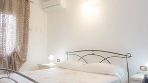 Une chambre à coucher avec un lit, des rideaux, des lampes de chevet et un climatiseur fixé au mur.