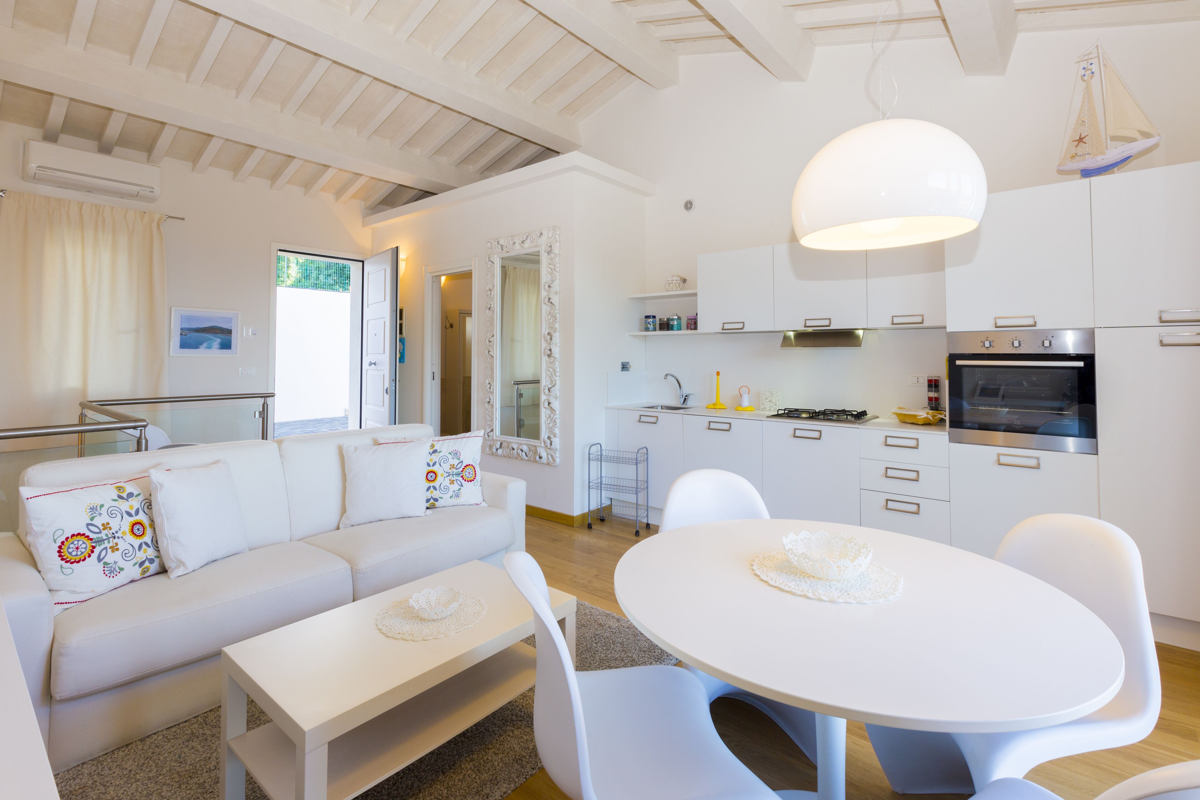Een moderne keuken met witte kasten, een grote oven en een eethoek met een ronde tafel en stoelen.
