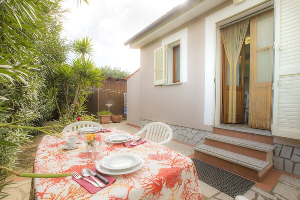 An outdoor dining area with a table set for four, surrounded by potted plants and a wooden fence. - Appartamenti La Casetta (Campo nell'Elba)