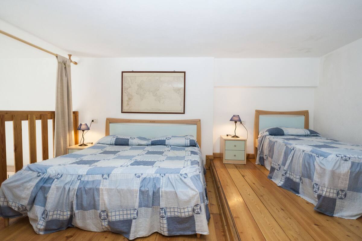 Quarto com duas camas, piso de madeira, mapa na parede e abajures.