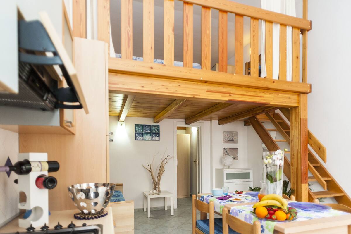 Quarto aconchegante com mezanino de madeira, área de refeições com fruteira e cozinha com adega.