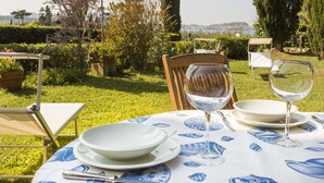 An outdoor dining setup with a table set for two, surrounded by greenery and a scenic view. - Villa Lilla (Portoferraio)