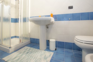 A bathroom with a shower, sink, and toilet.