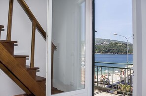 A wooden staircase leading to a balcony with a view of a beach and sea. - Trilocale Moby (Porto Azzurro)
