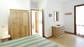 Un dormitorio con cama, cómoda, espejo y puerta que da a otra habitación.
