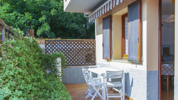 Un patio con una mesa y sillas, una valla de madera y un edificio con una ventana.