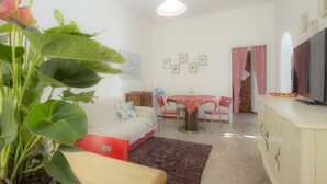 Una habitación acogedora con cama, una mesa de comedor con sillas, televisión y una planta grande.