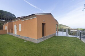 Um edifício térreo com teto plano, uma entrada pequena e um espaço de pátio pavimentado.