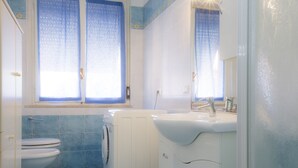 A bathroom with a toilet, washing machine, and sink. - Appartameno Mediterraneo (Campo nell'Elba)