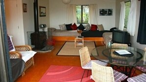 A cozy living room with a sofa, chairs, a glass table, and a fireplace. - Nestled Atop the Lane - Pukawa Bay Holiday Home (Pukawa Bay)
