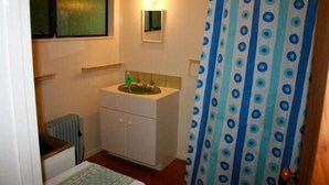 A small bathroom with a white sink, a mirror, and a shower curtain with a blue and white polka dot pattern. - Nestled Atop the Lane - Pukawa Bay Holiday Home (Pukawa Bay)