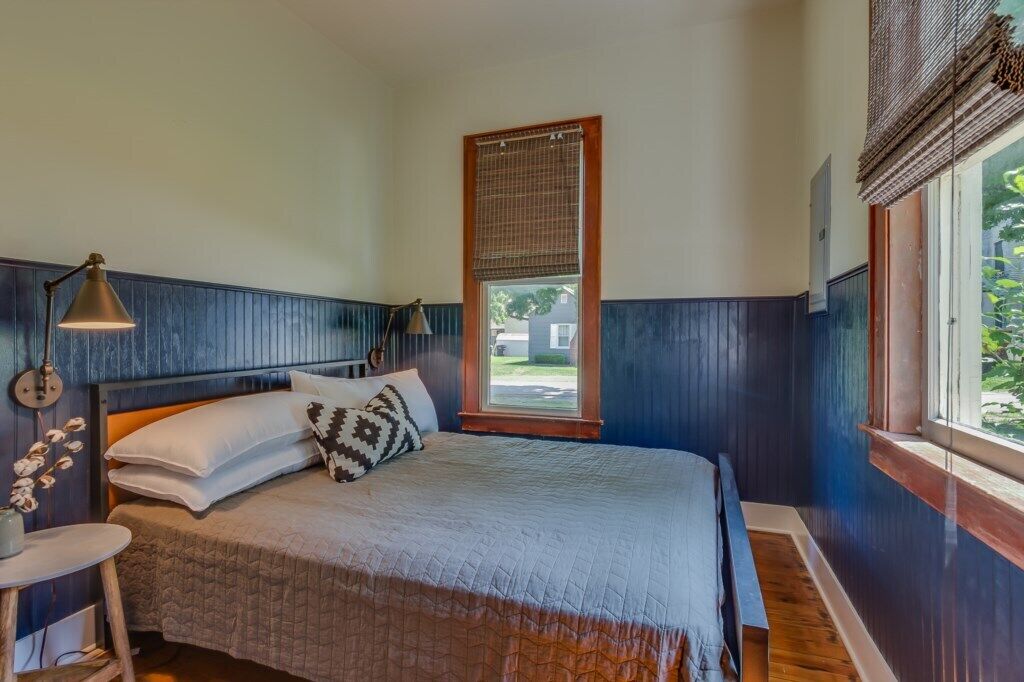 Une chambre à coucher avec un lit, une lampe de chevet, une fenêtre et une vue sur l’extérieur.