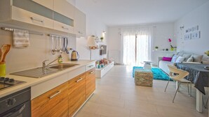 A modern kitchen with a built-in oven, a sink, and wooden cabinets. There is a dining area with a table and chairs, and a living room with a sofa and a coffee table. - Apartment 1345/12663 (Istria - Pula), 2000m from the beach (Pula)